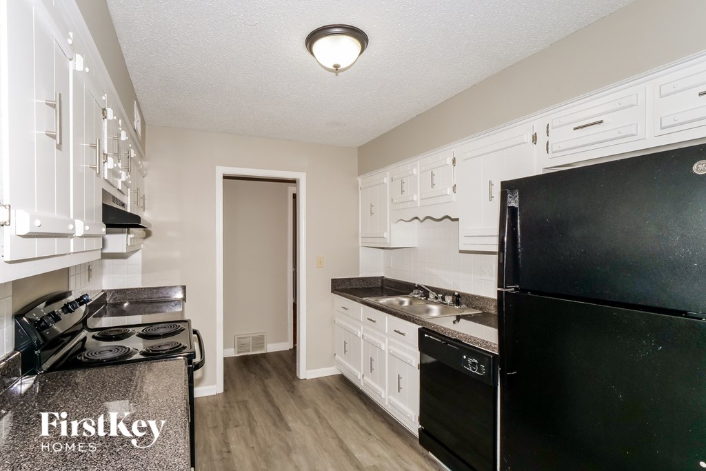 A kitchen with a black fridge and white cabinets.