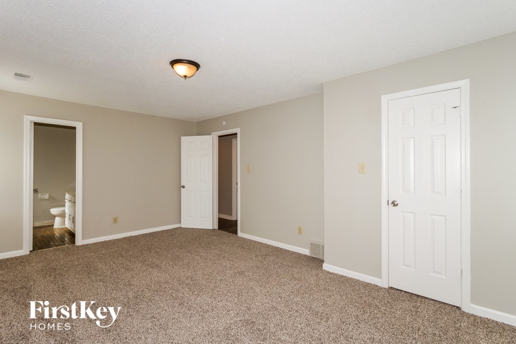 A spacious room with a carpeted floor and a ceiling light fixture.