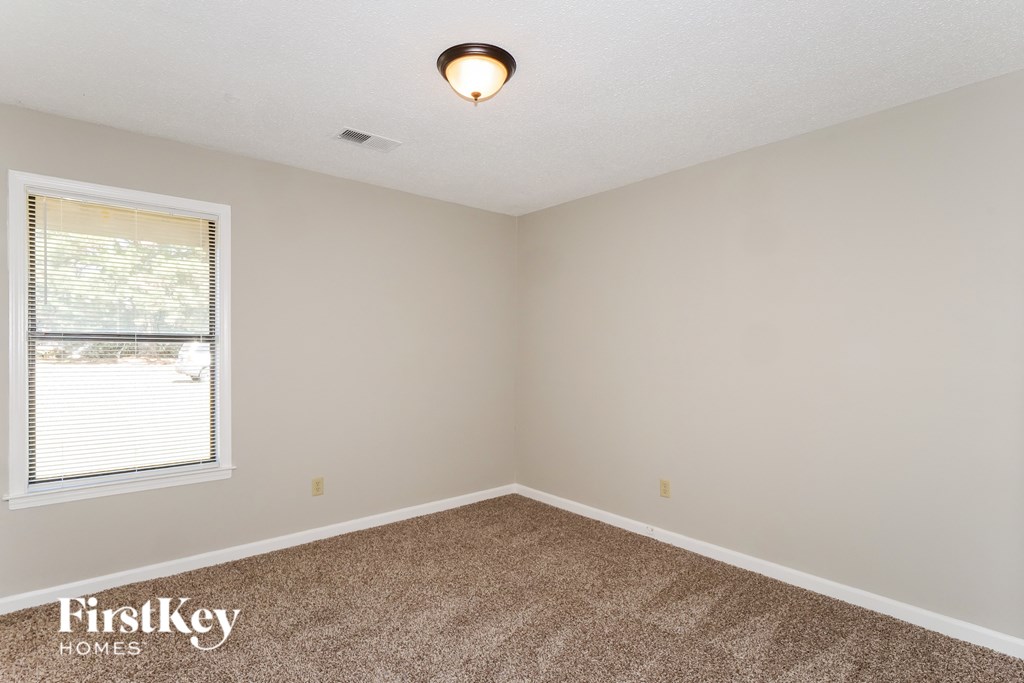 A room with a carpeted floor and a window with blinds.