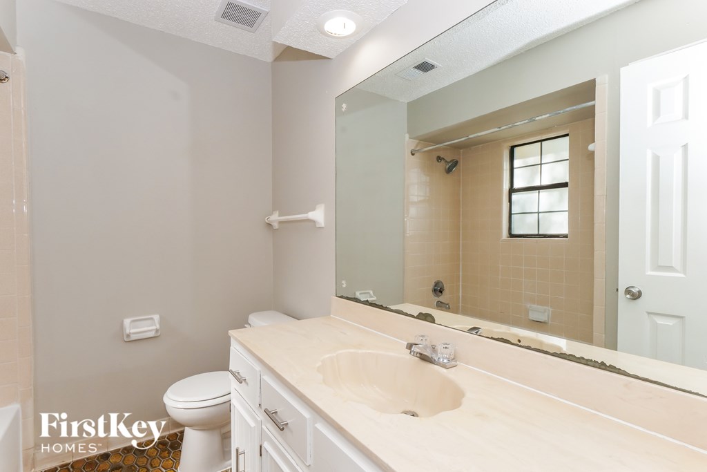 A bathroom with a sink, toilet and mirror.