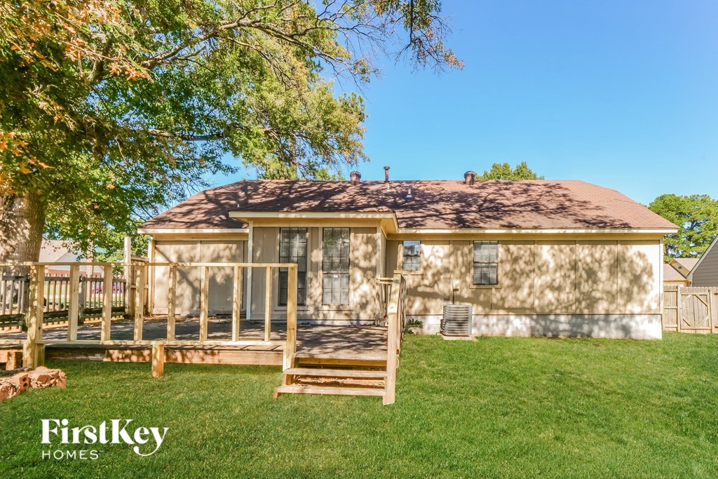 A house with a brown roof and a porch is surrounded by trees.