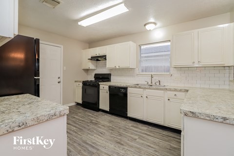 a white kitchen with black appliances and white cabinets