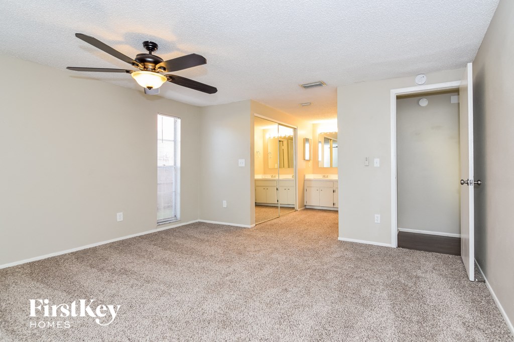 a spacious living room with carpet and a ceiling fan