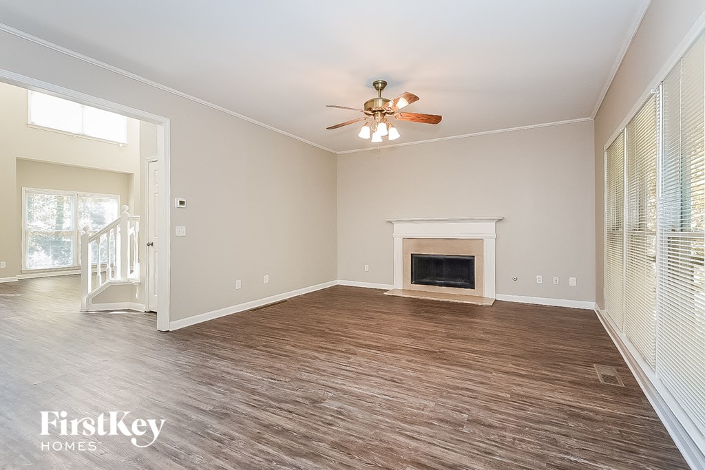A spacious living room with a fireplace and a ceiling fan.