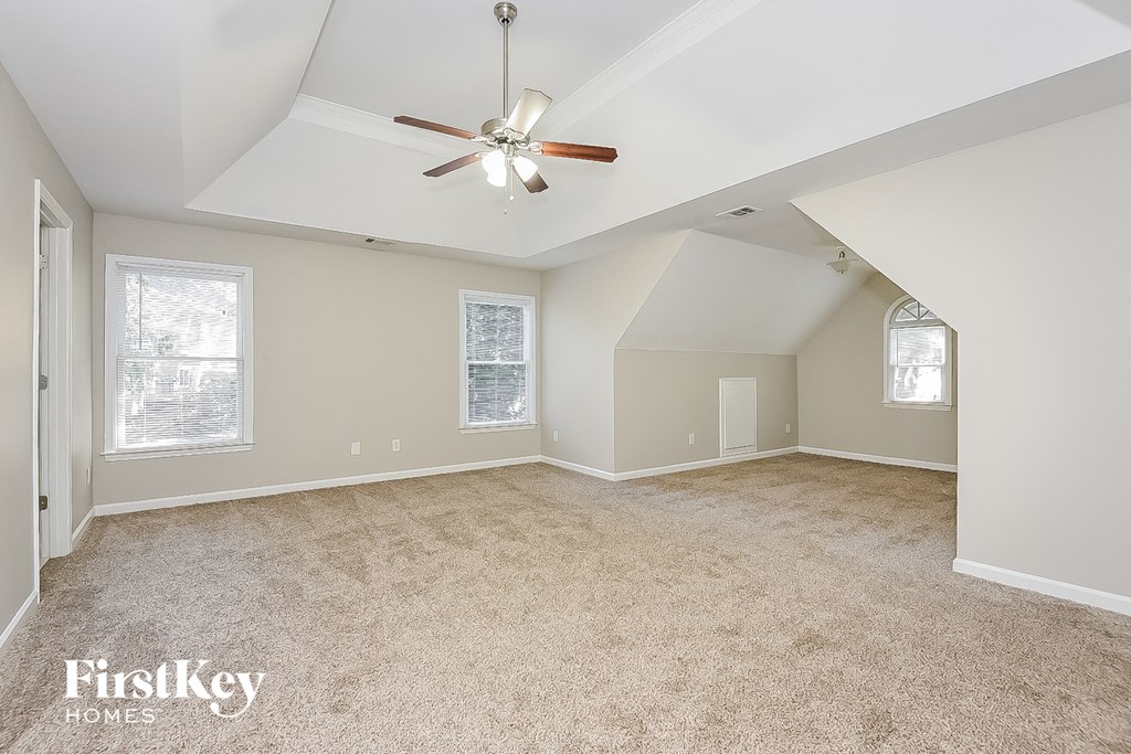 A spacious room with a ceiling fan and carpeted floor.
