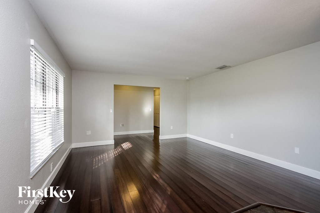 an empty living room with wood floors and white walls