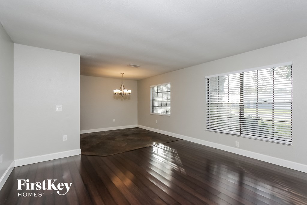 an empty living room with wood floors and a large window