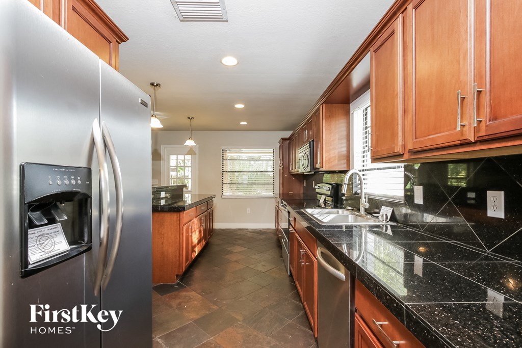 a kitchen with black countertops and wood cabinets and stainless steel appliances