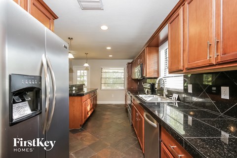 a kitchen with black countertops and wood cabinets and stainless steel appliances