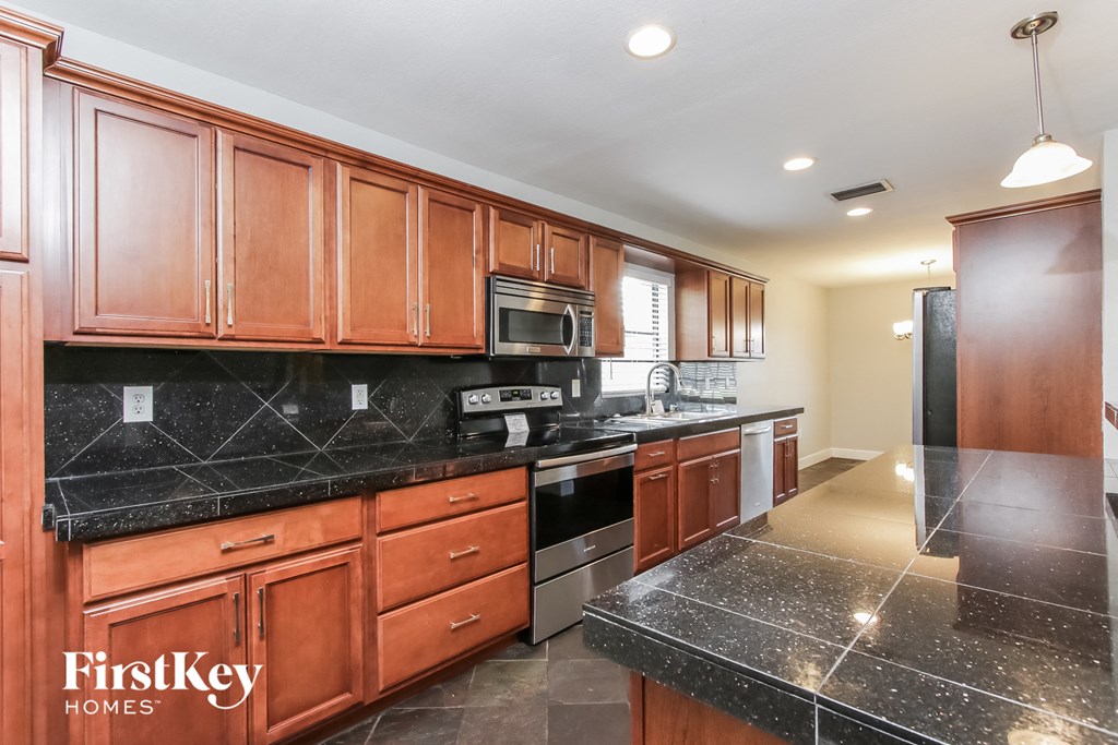 a kitchen with black granite counter tops and wooden cabinets