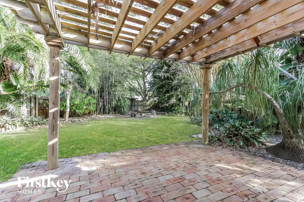 a backyard with a wooden pergola and a brick patio