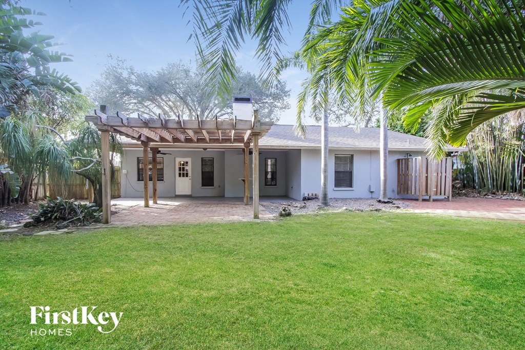 a small white house with a lawn and palm trees