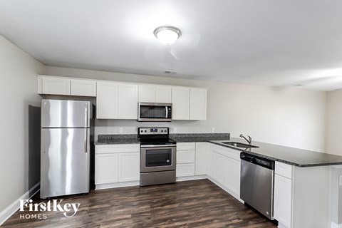 A kitchen with a stainless steel refrigerator, microwave, oven, and sink.
