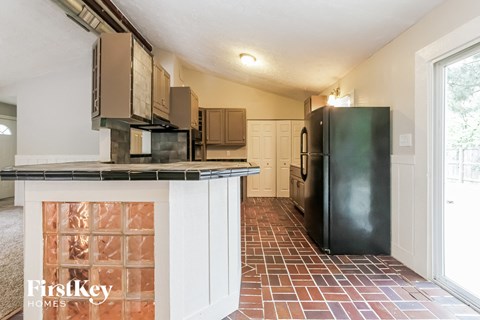 A kitchen with a black fridge and brown cabinets.