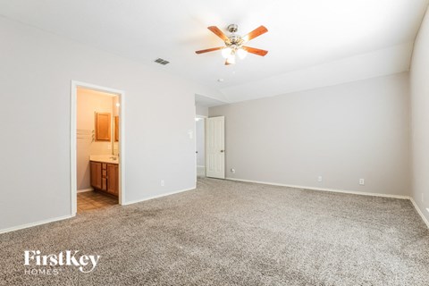 a spacious living room with carpet and a ceiling fan