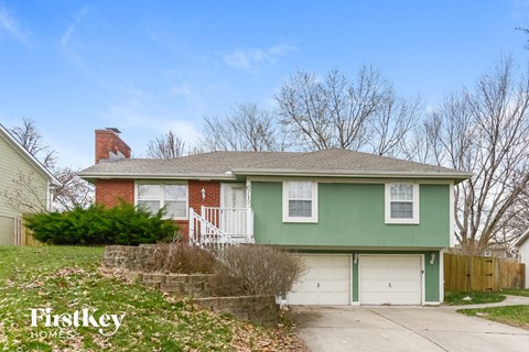 a green house with a white garage door