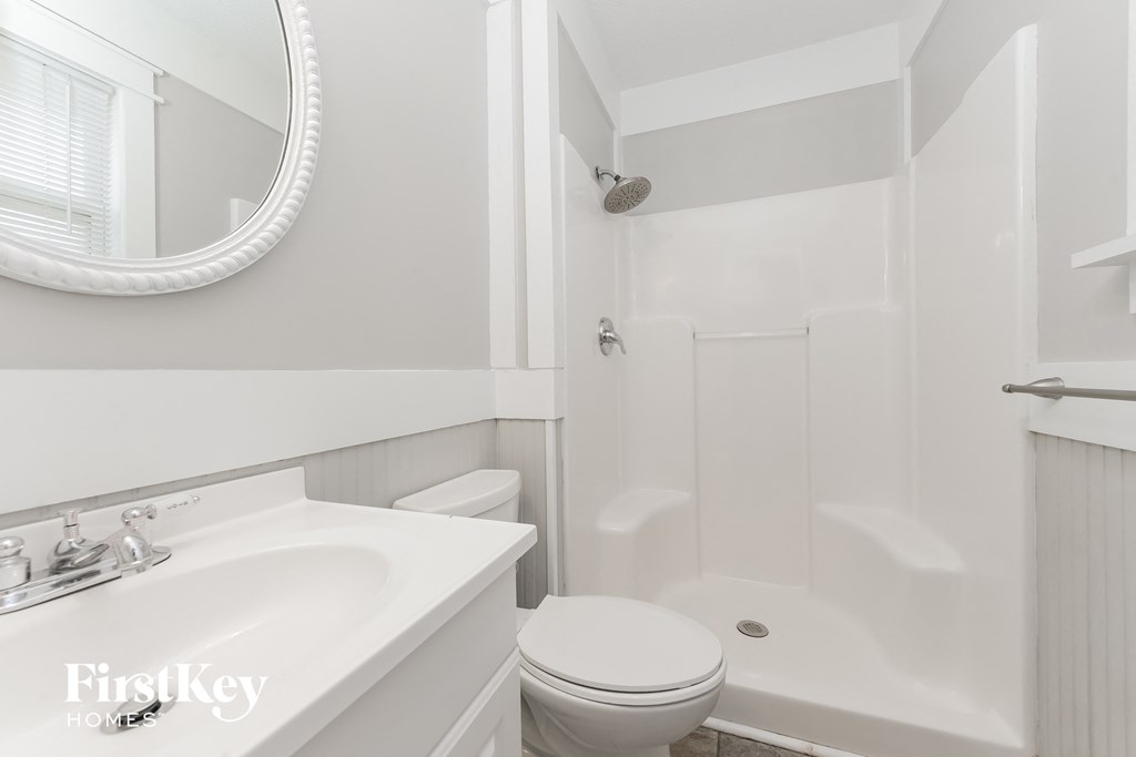 a white bathroom with a toilet and a sink and a shower