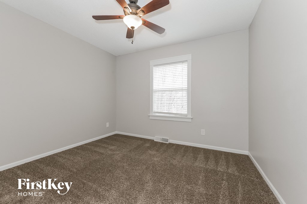 an empty room with a ceiling fan and a window