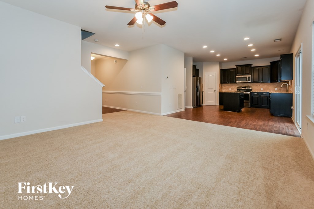 an empty living room and kitchen with a ceiling fan