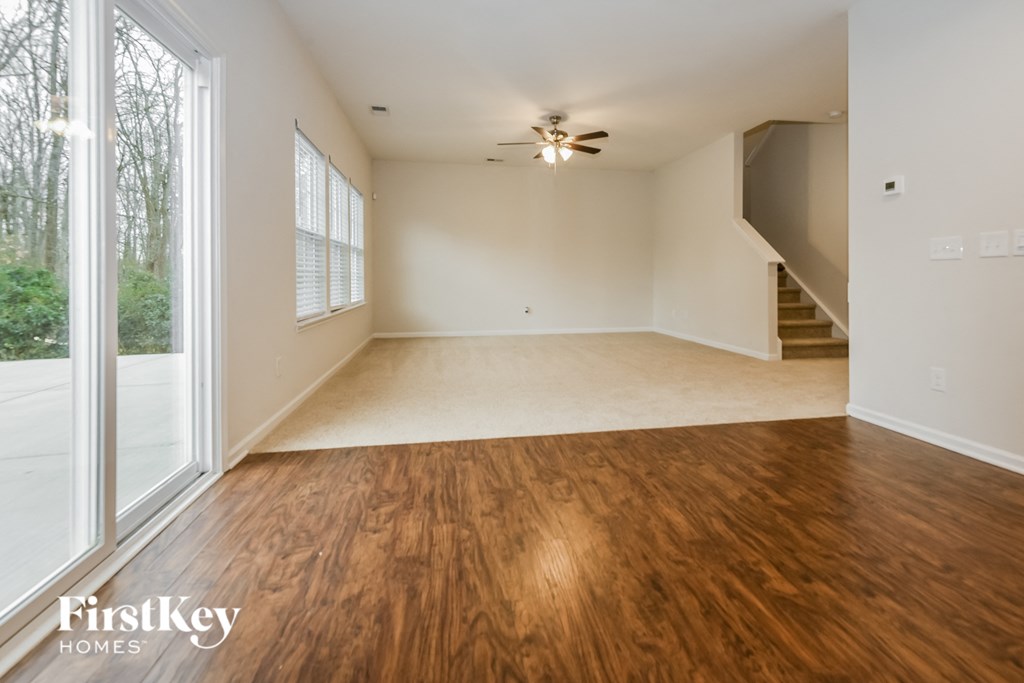 an empty living room with wood flooring and a ceiling fan