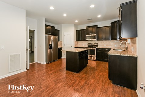 a kitchen with black cabinets and stainless steel appliances and a wooden floor