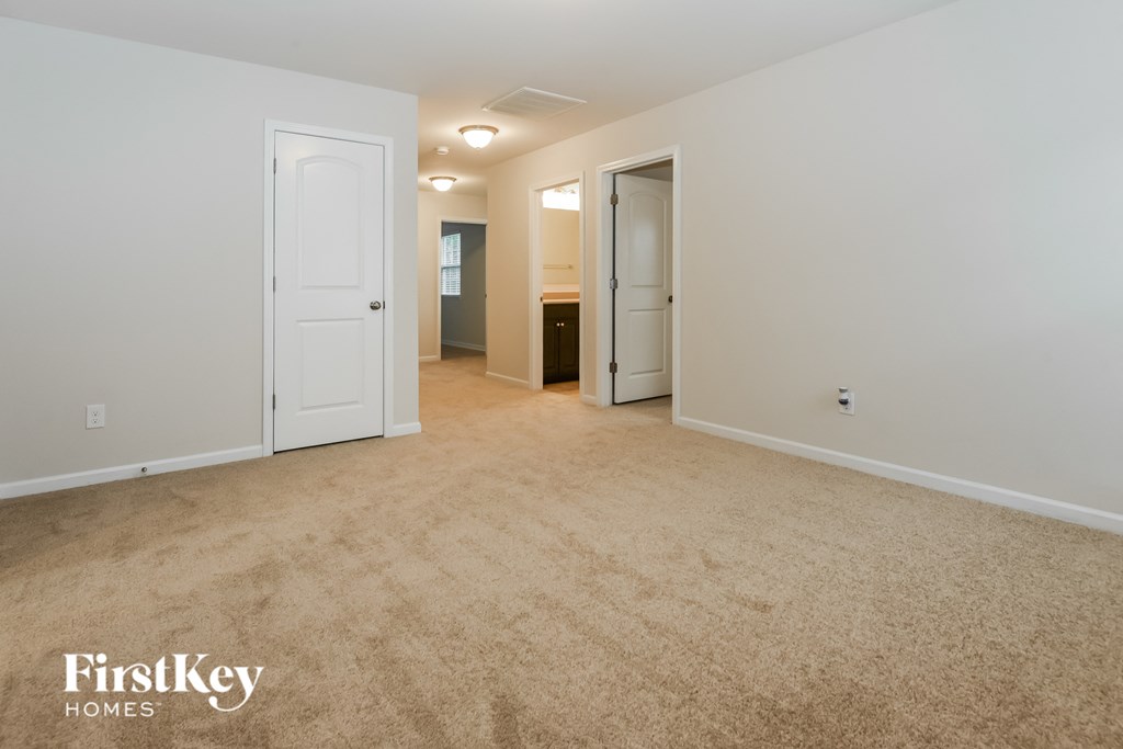 a spacious living room with a carpeted floor and a door to a bathroom