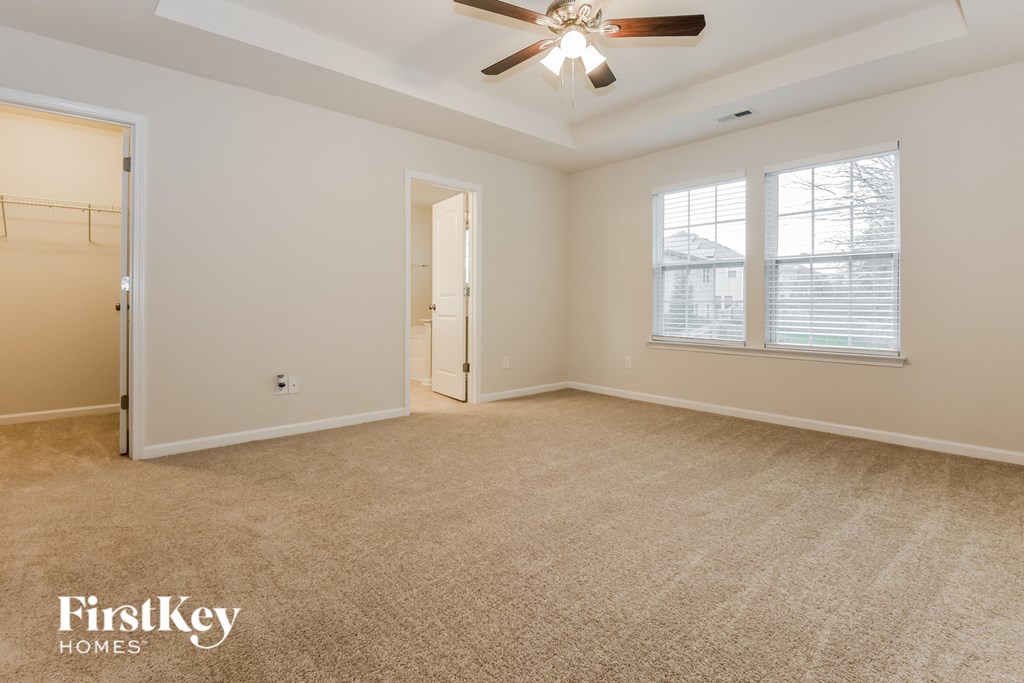 an empty living room with a ceiling fan and a door to a closet