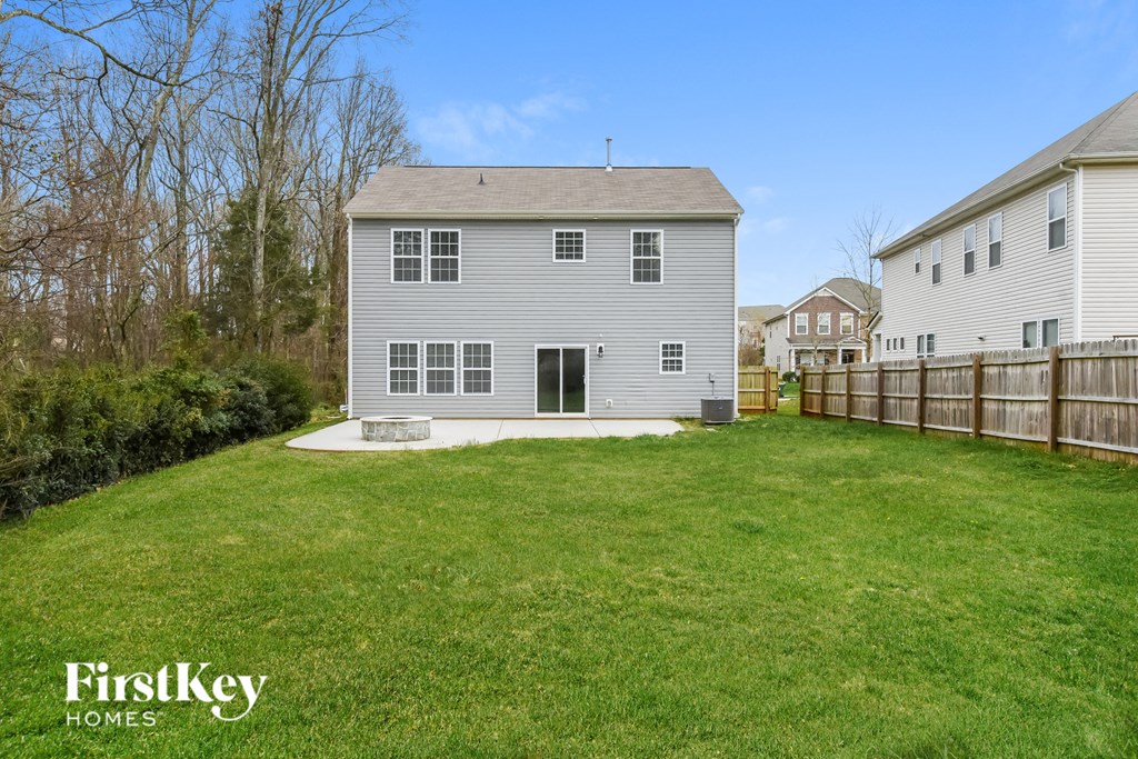 a backyard with a white house and a wooden fence