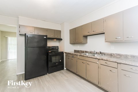 A kitchen with a black fridge and beige cabinets.