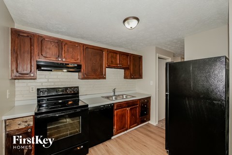 A kitchen with wooden cabinets and a black refrigerator.