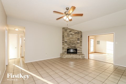 a living room with a stone fireplace and a ceiling fan