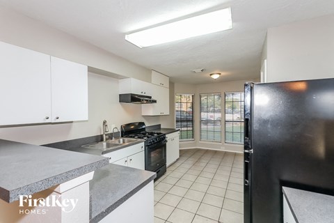 a kitchen with white cabinets and black appliances and a window