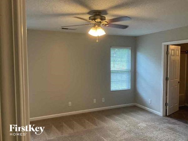 A room with a ceiling fan and a window with blinds.