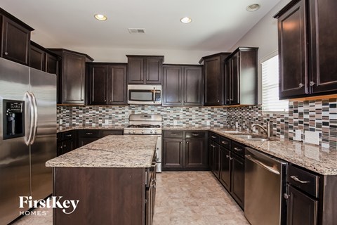 a kitchen with dark cabinets and granite counter tops and stainless steel appliances
