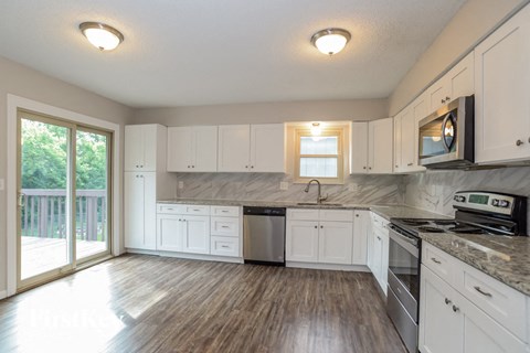 A kitchen with white cabinets and a wooden floor.