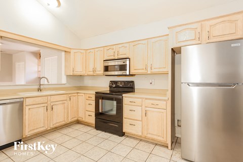 A kitchen with wooden cabinets and a stainless steel refrigerator.