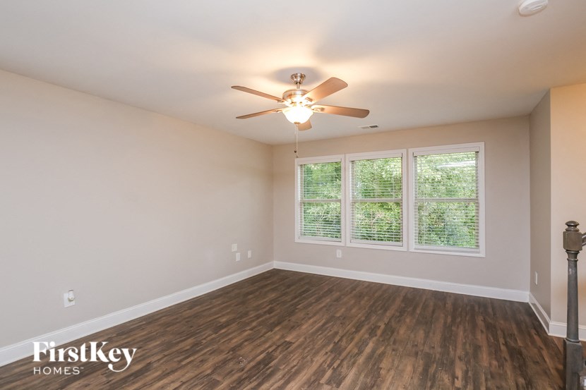 A room with a ceiling fan and wooden flooring.