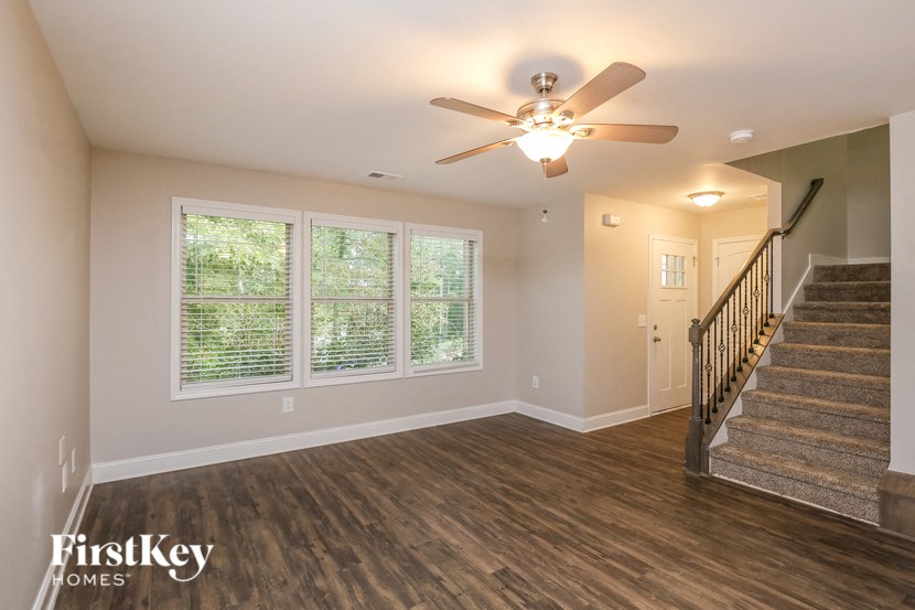 A spacious room with wooden floors and a staircase leading to another room.