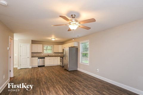 A spacious kitchen and living room with a ceiling fan and wooden floors.