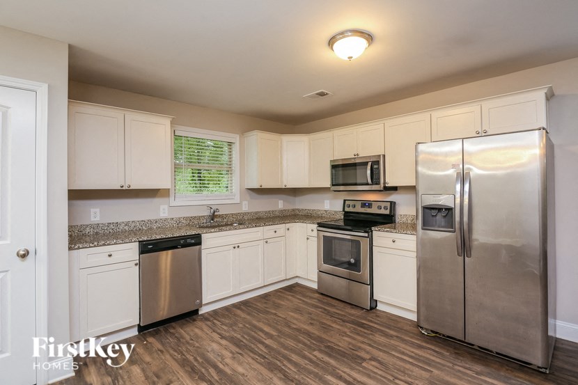 A kitchen with a stainless steel refrigerator, microwave, and oven.