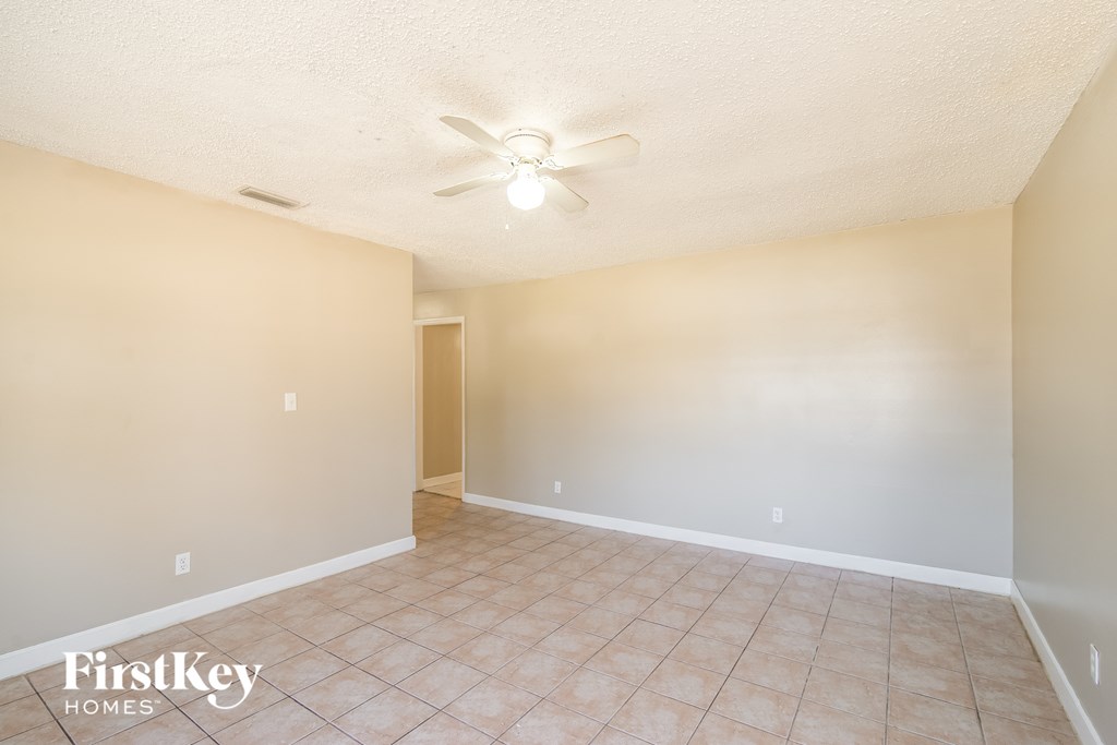a empty living room with a ceiling fan and a tiled floor