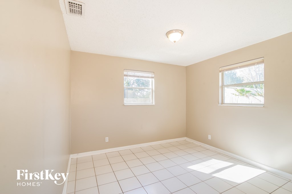 an empty room with a white tiled floor and two windows