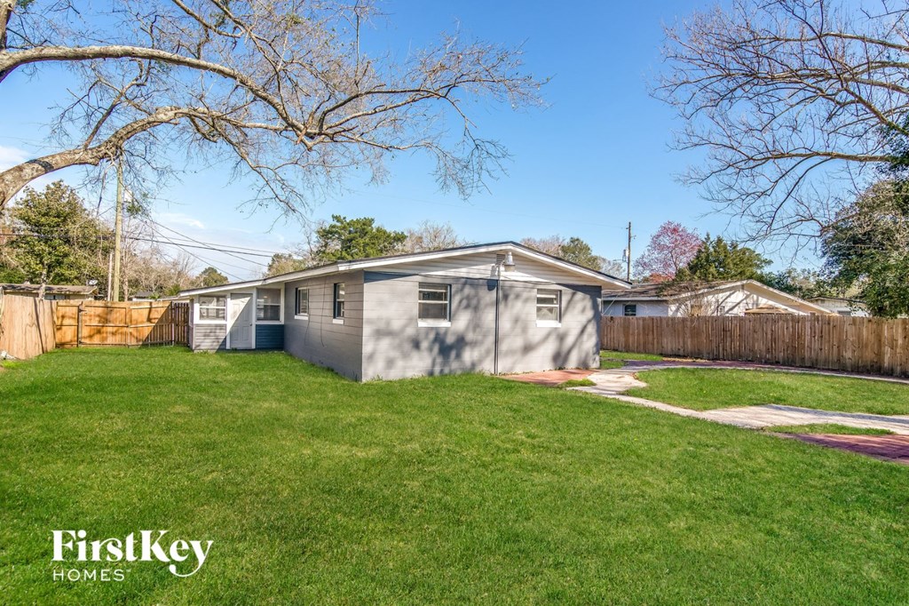 a small gray house in a backyard with grass and a tree