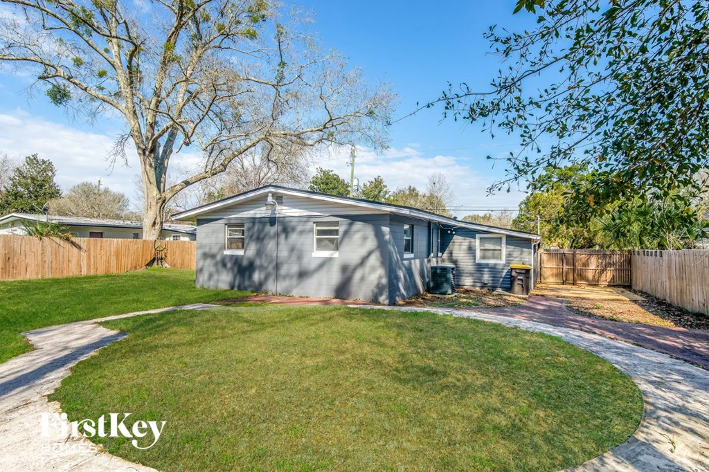 a small mobile home in a backyard with a lawn and a tree