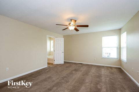 a living room with carpet and a ceiling fan