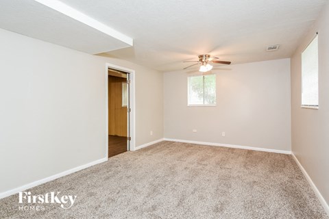a spacious living room with carpet and a ceiling fan