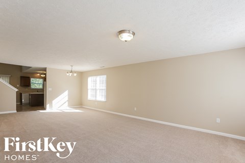 A spacious room with a carpeted floor and a light fixture on the ceiling.