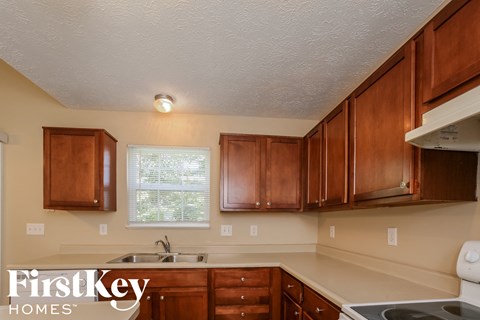 A kitchen with wooden cabinets and a stove top oven.