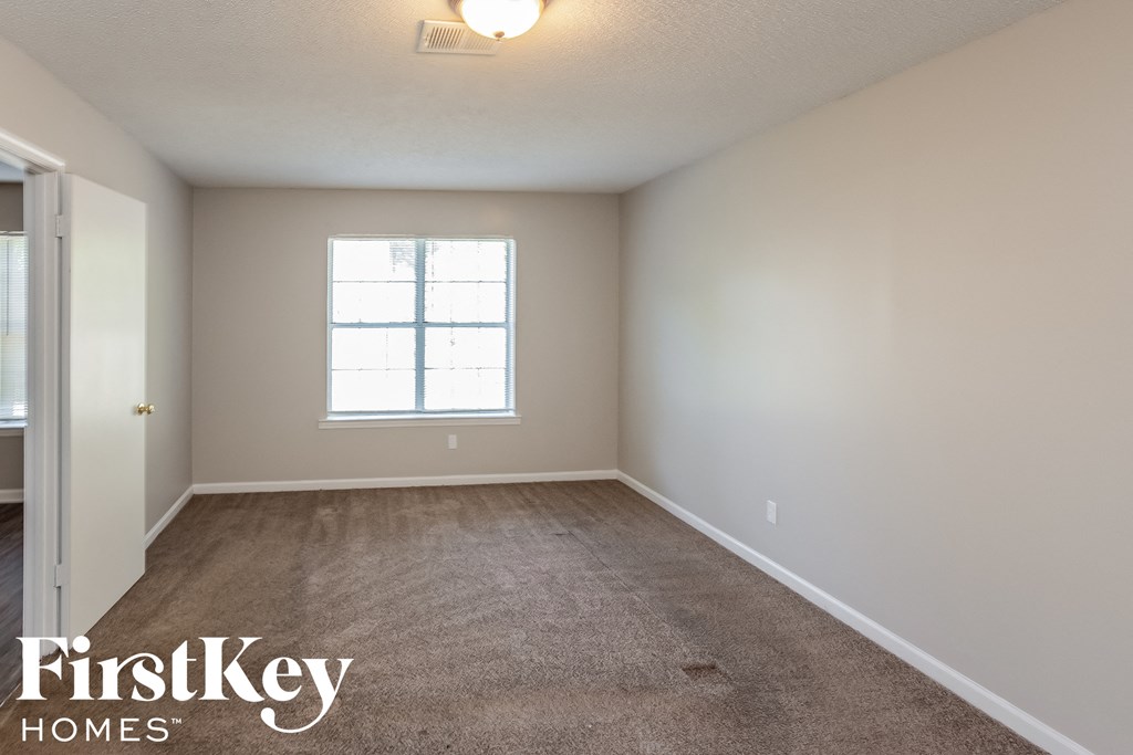 A room with a carpeted floor and a window.