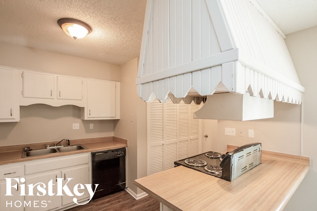 A kitchen with a stove top oven and a wooden counter top.